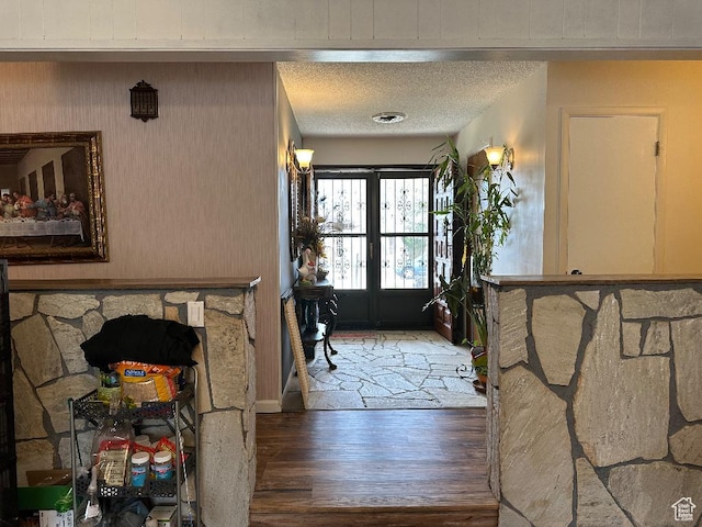 entrance foyer featuring a textured ceiling, wood finished floors, and french doors