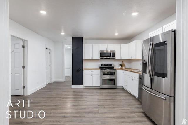 233 Patterson St, Ogden, UT 84401 - kitchen featuring recessed lighting, stainless steel appliances, light wood-style floors, white cabinets, and butcher block counters