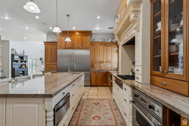 189 E Weber Canyon Rd, Oakley, UT 84055 - kitchen with appliances with stainless steel finishes, light stone counters, brown cabinetry, glass insert cabinets, and a warming drawer