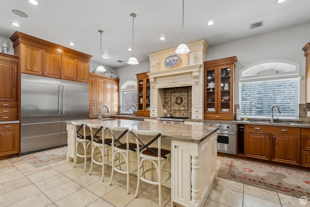 189 E Weber Canyon Rd, Oakley, UT 84055 - kitchen with light stone counters, a sink, brown cabinetry, stainless steel appliances, and visible vents