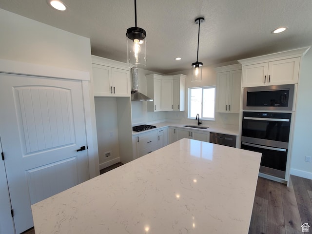 kitchen featuring built in microwave, a sink, gas stovetop, wall chimney range hood, and white cabinets