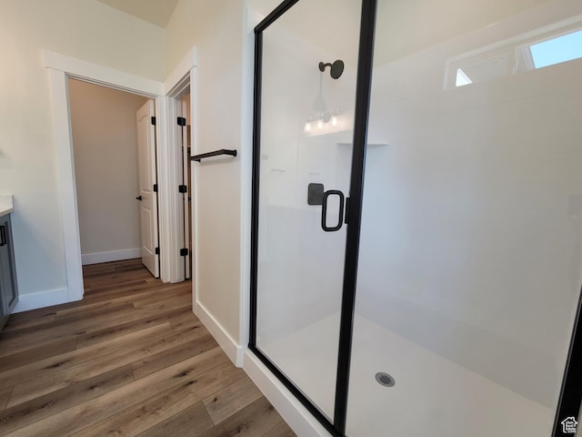 bathroom featuring a stall shower, baseboards, wood finished floors, and vanity
