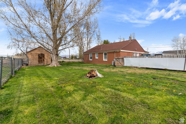 view of yard featuring cooling unit, an outdoor structure, a fenced backyard, a storage unit, and a fire pit