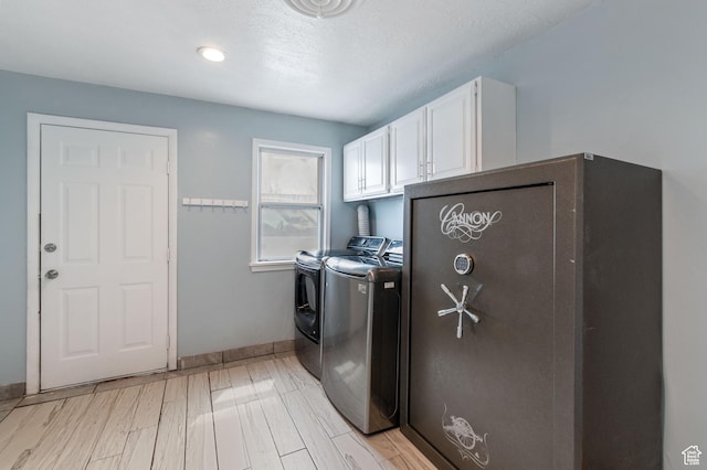 laundry area with light wood-style floors, baseboards, cabinet space, and washer and clothes dryer