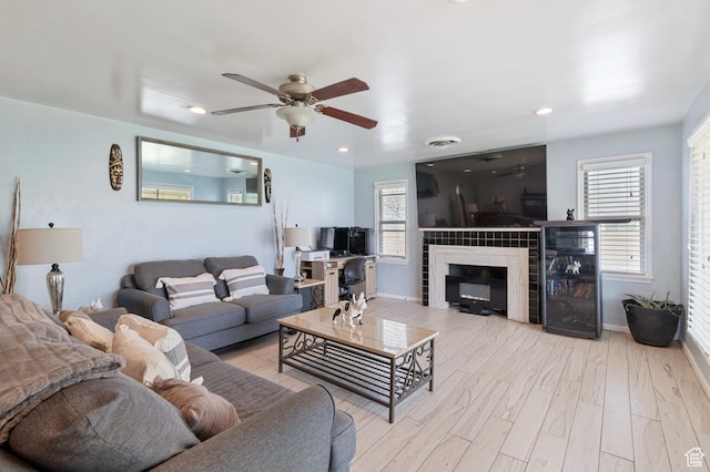 living area with baseboards, ceiling fan, a fireplace, and wood finished floors
