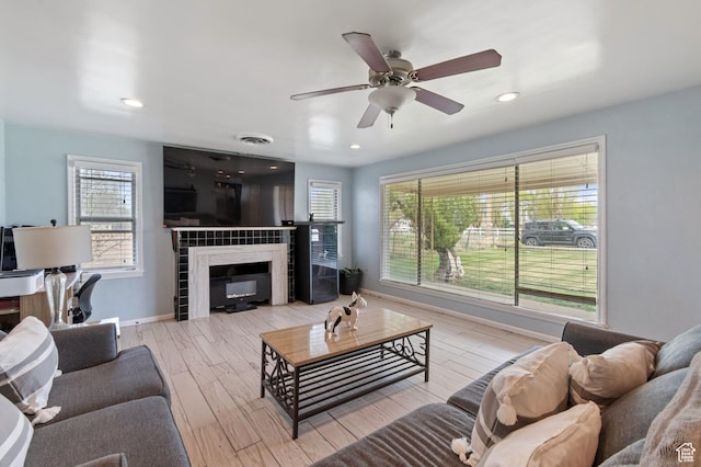 living area featuring wood finished floors, baseboards, a healthy amount of sunlight, and a tile fireplace
