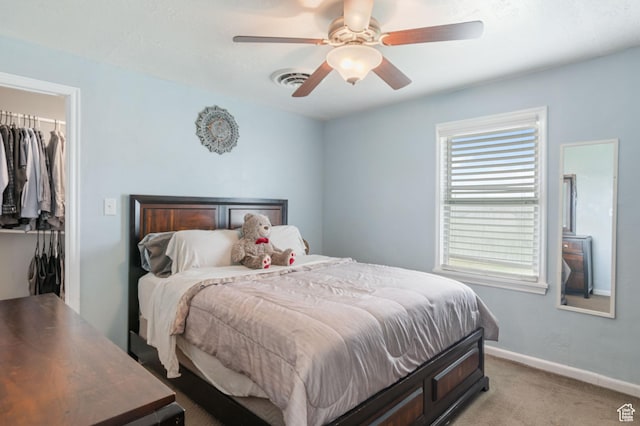 bedroom with a walk in closet, ceiling fan, visible vents, a closet, and light carpet
