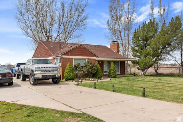 ranch-style home with a chimney, concrete driveway, and a front lawn