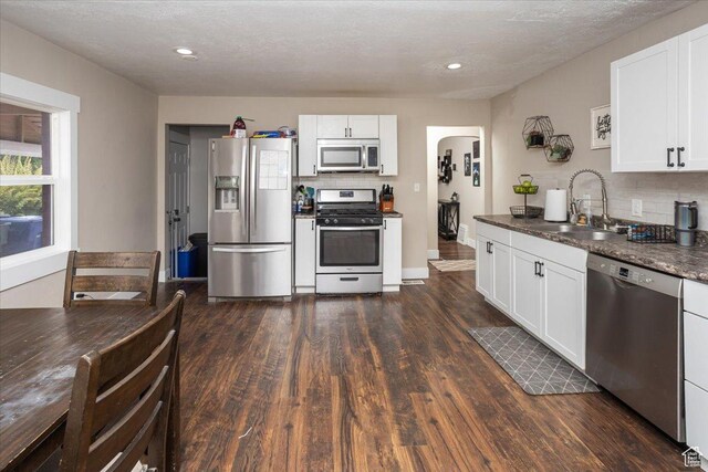 3048 S Harrison Blvd, Ogden, UT 84403 - kitchen with a sink, dark wood-style flooring, decorative backsplash, arched walkways, and appliances with stainless steel finishes