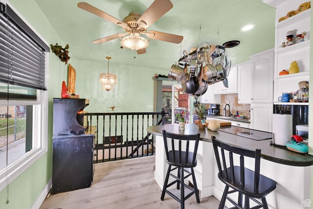 162 Mond St, Ogden, UT 84404 - kitchen with tasteful backsplash, white cabinets, light wood finished floors, a peninsula, and a kitchen breakfast bar