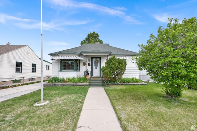 bungalow-style home with roof with shingles and a front yard