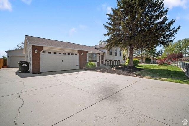 2009 W 7455 S, West Jordan, UT 84084 - tri-level home with a front yard, brick siding, concrete driveway, an attached garage, and fence