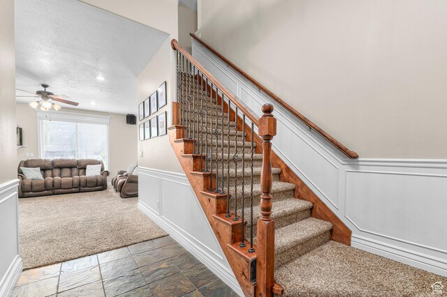 2254 N 1560 W, Pleasant Grove, UT 84062 - stairway with stone tile floors, a ceiling fan, a decorative wall, a textured ceiling, and wainscoting
