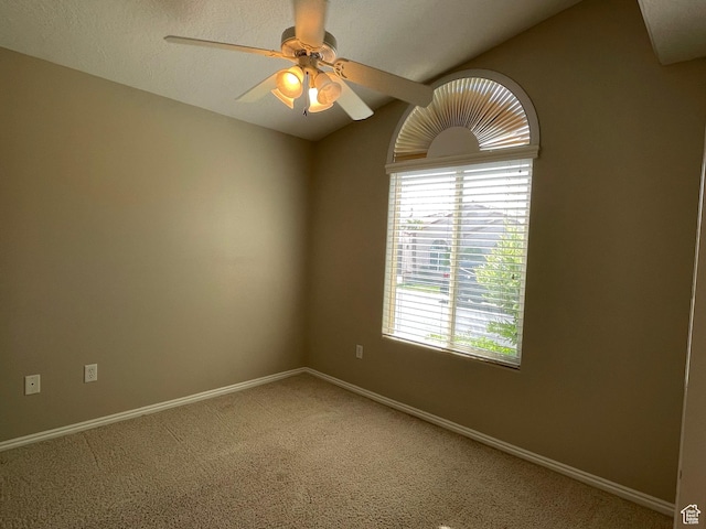 empty room featuring baseboards, light carpet, ceiling fan, and vaulted ceiling