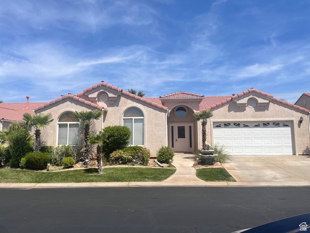 mediterranean / spanish home with stucco siding, a tile roof, driveway, and an attached garage