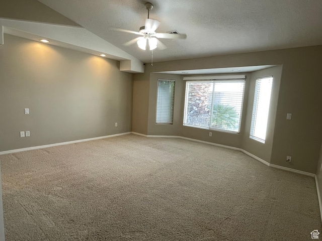 carpeted empty room with baseboards, a ceiling fan, a textured ceiling, and vaulted ceiling