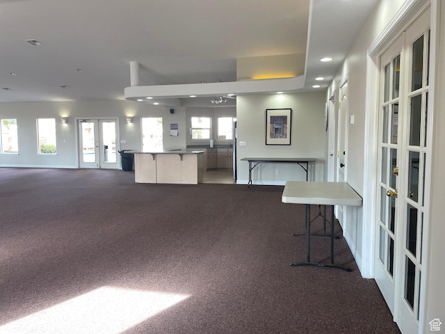 interior space with a breakfast bar, open floor plan, dark carpet, and french doors