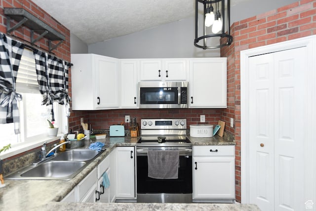26 Orchard Ln S, Grantsville, UT 84029 - kitchen featuring lofted ceiling, a textured ceiling, white cabinets, a sink, and stainless steel appliances