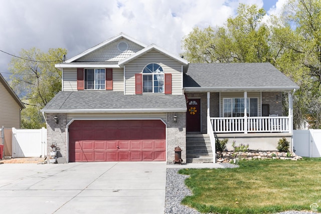 tri-level home featuring a porch, driveway, an attached garage, and a gate