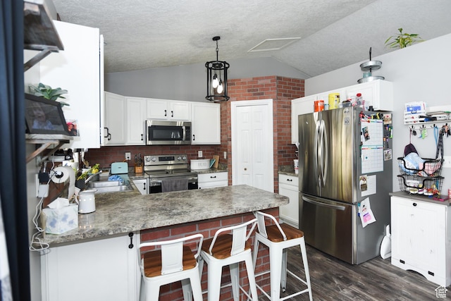 26 Orchard Ln S, Grantsville, UT 84029 - kitchen with appliances with stainless steel finishes, a sink, dark wood finished floors, a peninsula, and lofted ceiling
