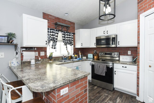 26 Orchard Ln S, Grantsville, UT 84029 - kitchen with dark wood-style flooring, appliances with stainless steel finishes, a sink, a peninsula, and white cabinetry