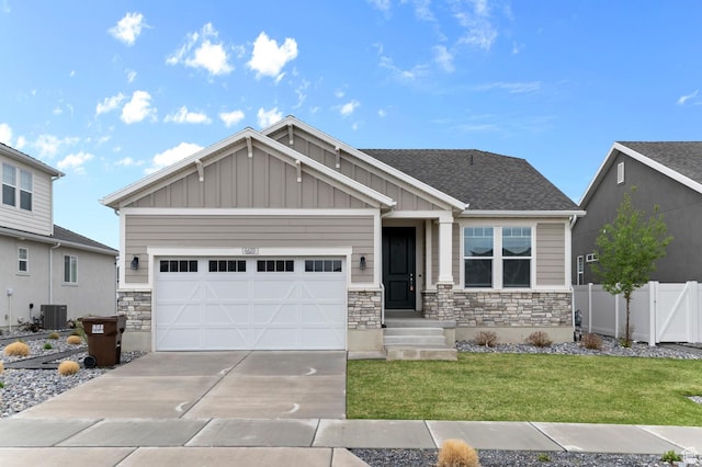 craftsman-style home featuring driveway, board and batten siding, stone siding, fence, and a front lawn
