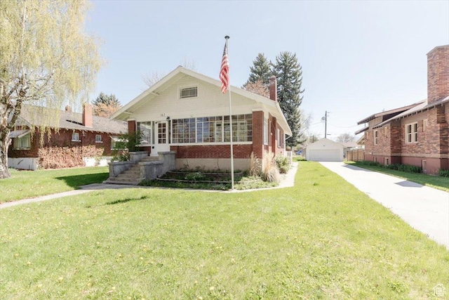 bungalow-style home featuring a detached garage, an outdoor structure, and a front yard