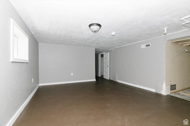unfurnished living room with finished concrete flooring, baseboards, a textured ceiling, and visible vents