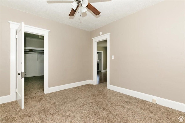 unfurnished bedroom featuring a closet, baseboards, a spacious closet, a ceiling fan, and carpet