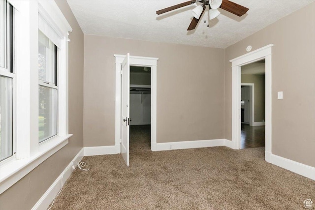 unfurnished bedroom featuring a walk in closet, multiple windows, baseboards, and carpet flooring