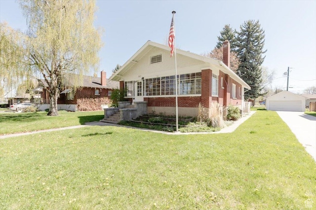 bungalow with brick siding, a front lawn, a chimney, and a detached garage