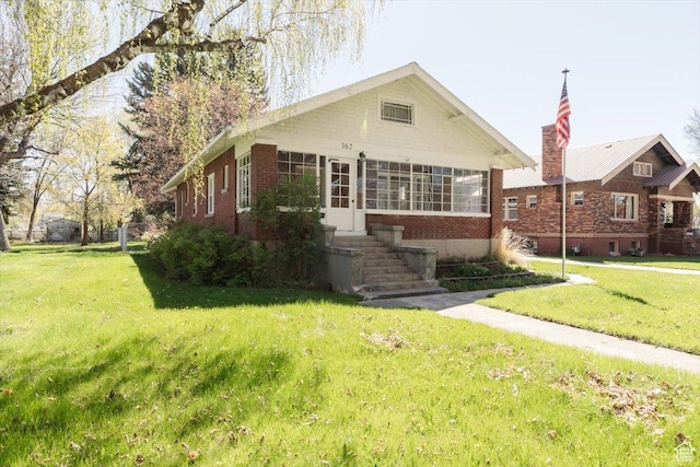 bungalow-style house featuring brick siding and a front yard