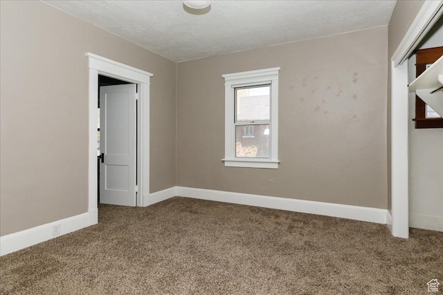 carpeted spare room with a textured ceiling and baseboards