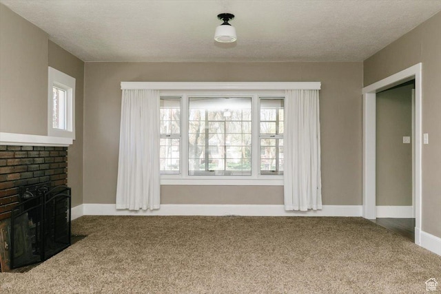 unfurnished living room featuring a textured ceiling, baseboards, carpet, and a fireplace