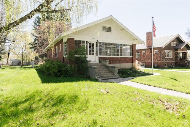 bungalow with a front lawn and brick siding