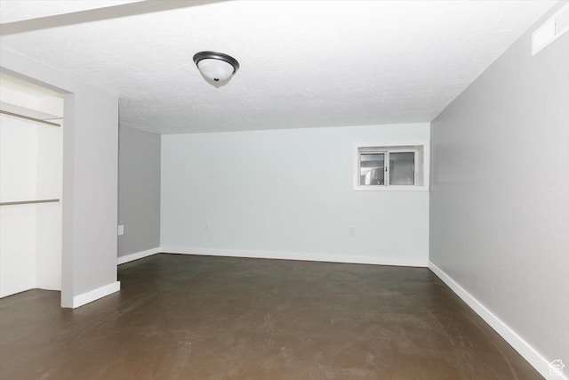 below grade area with a textured ceiling, baseboards, and visible vents