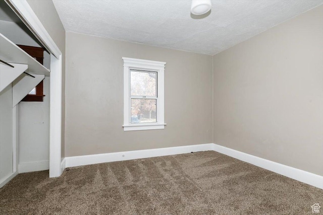unfurnished bedroom with carpet floors, a textured ceiling, and baseboards