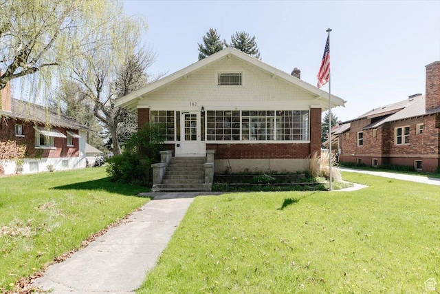 bungalow-style home featuring brick siding and a front lawn