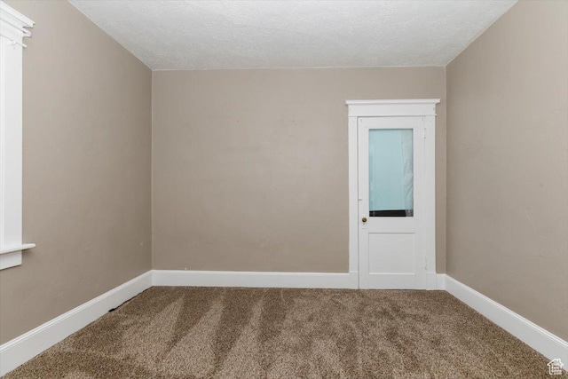 carpeted spare room featuring baseboards and a textured ceiling