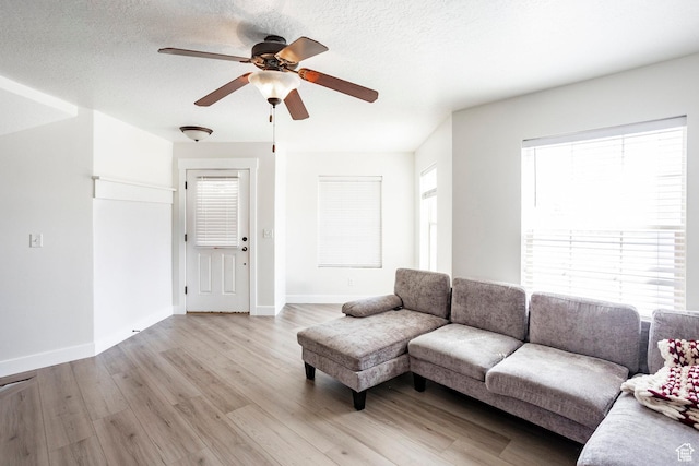 living room with ceiling fan, light wood-style flooring, and baseboards