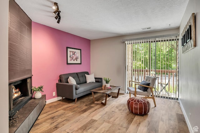 2270 E 4500 S Unit 2A, Holladay, UT 84117 - living area featuring wood finished floors, a textured ceiling, baseboards, and a large fireplace