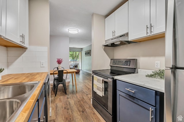 2270 E 4500 S Unit 2A, Holladay, UT 84117 - kitchen with appliances with stainless steel finishes, under cabinet range hood, butcher block countertops, hardwood / wood-style flooring, and white cabinets