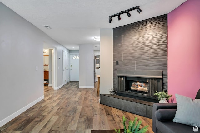 2270 E 4500 S Unit 2A, Holladay, UT 84117 - living area featuring baseboards, wood finished floors, a multi sided fireplace, and track lighting