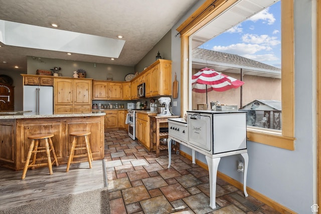 875 W Oak Ln, Francis, UT 84036 - kitchen with light stone countertops, a skylight, stainless steel appliances, baseboards, and visible vents