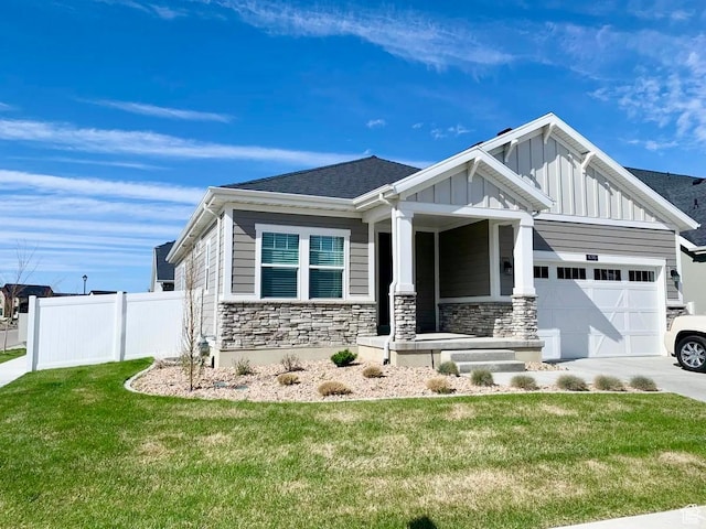 craftsman house with driveway, stone siding, a front yard, an attached garage, and fence
