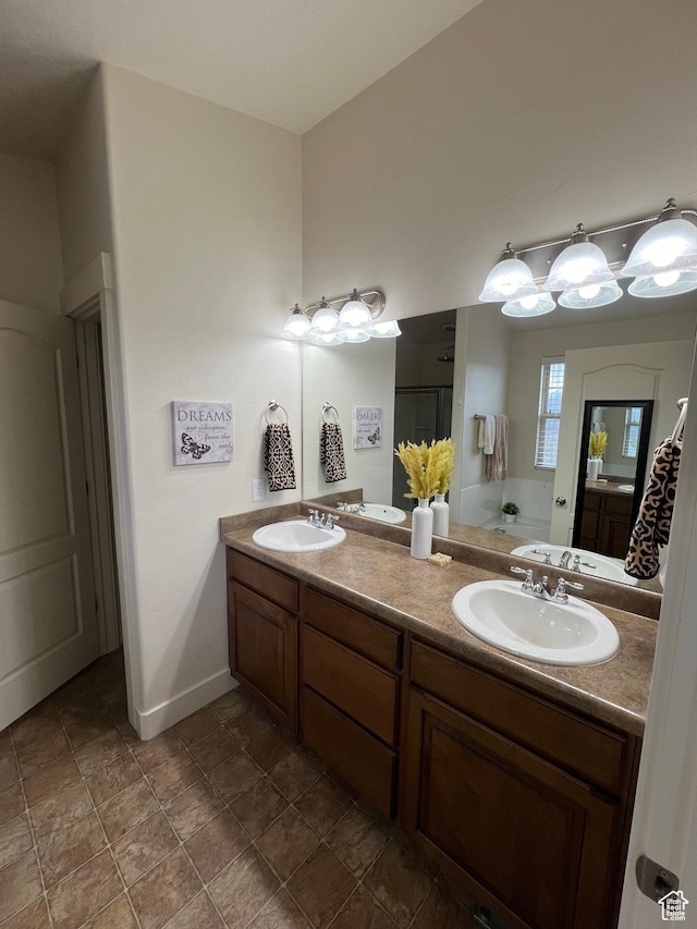 bathroom with double vanity, baseboards, walk in shower, and a sink