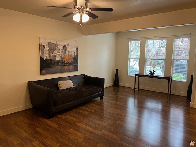 living area with baseboards, a ceiling fan, and wood finished floors