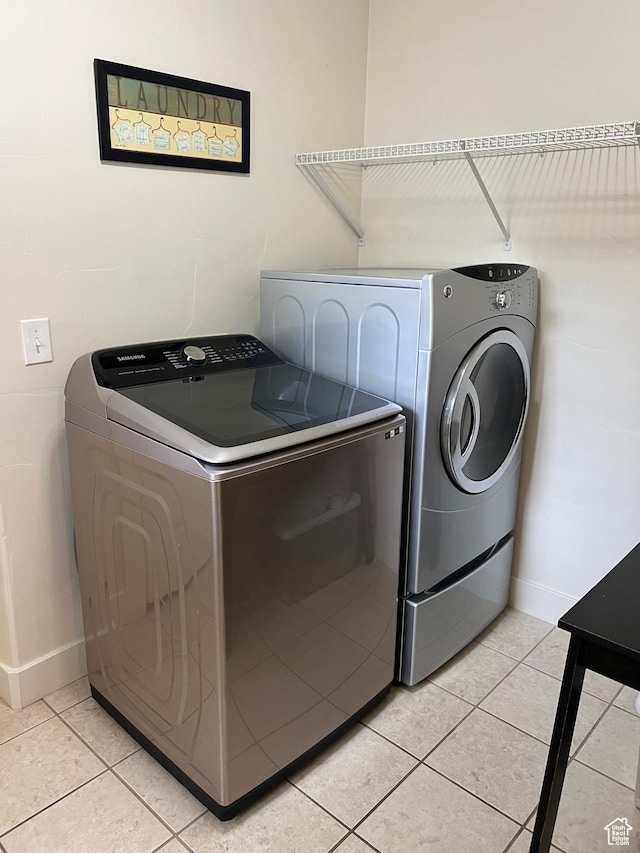 laundry room with light tile patterned floors, separate washer and dryer, baseboards, and laundry area