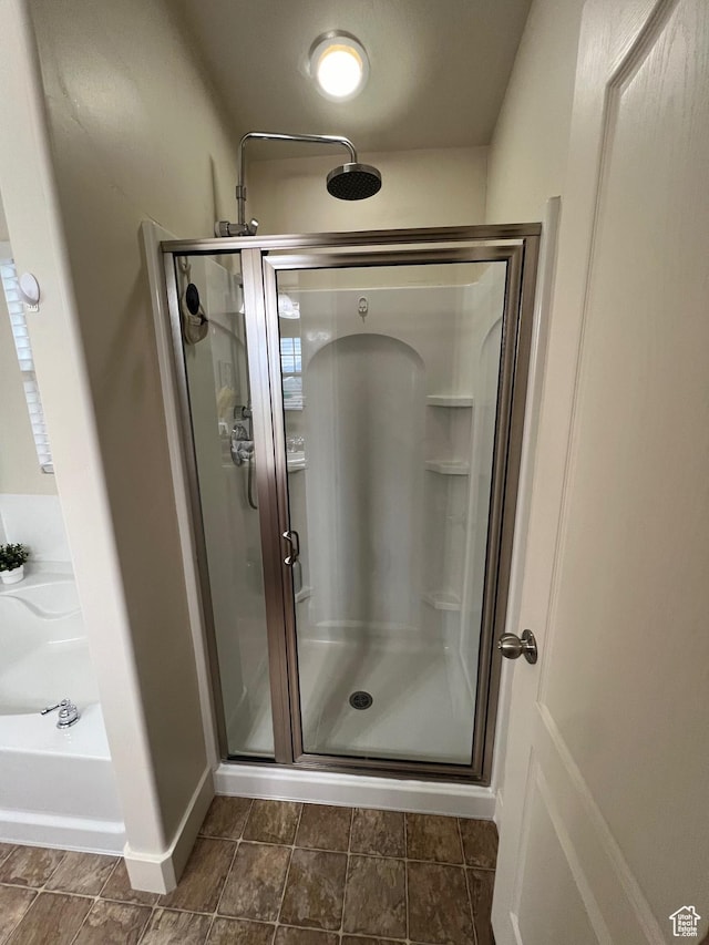 bathroom with baseboards, a shower stall, and a garden tub