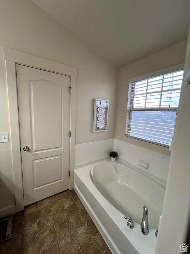 bathroom with stone finish floor, lofted ceiling, and a garden tub